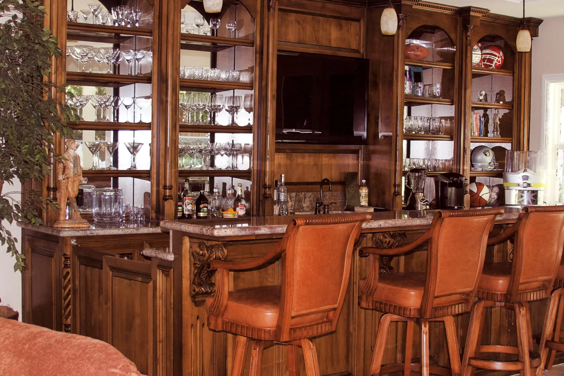 Custom-built bar with detailed millwork, glass shelving, and stone counter