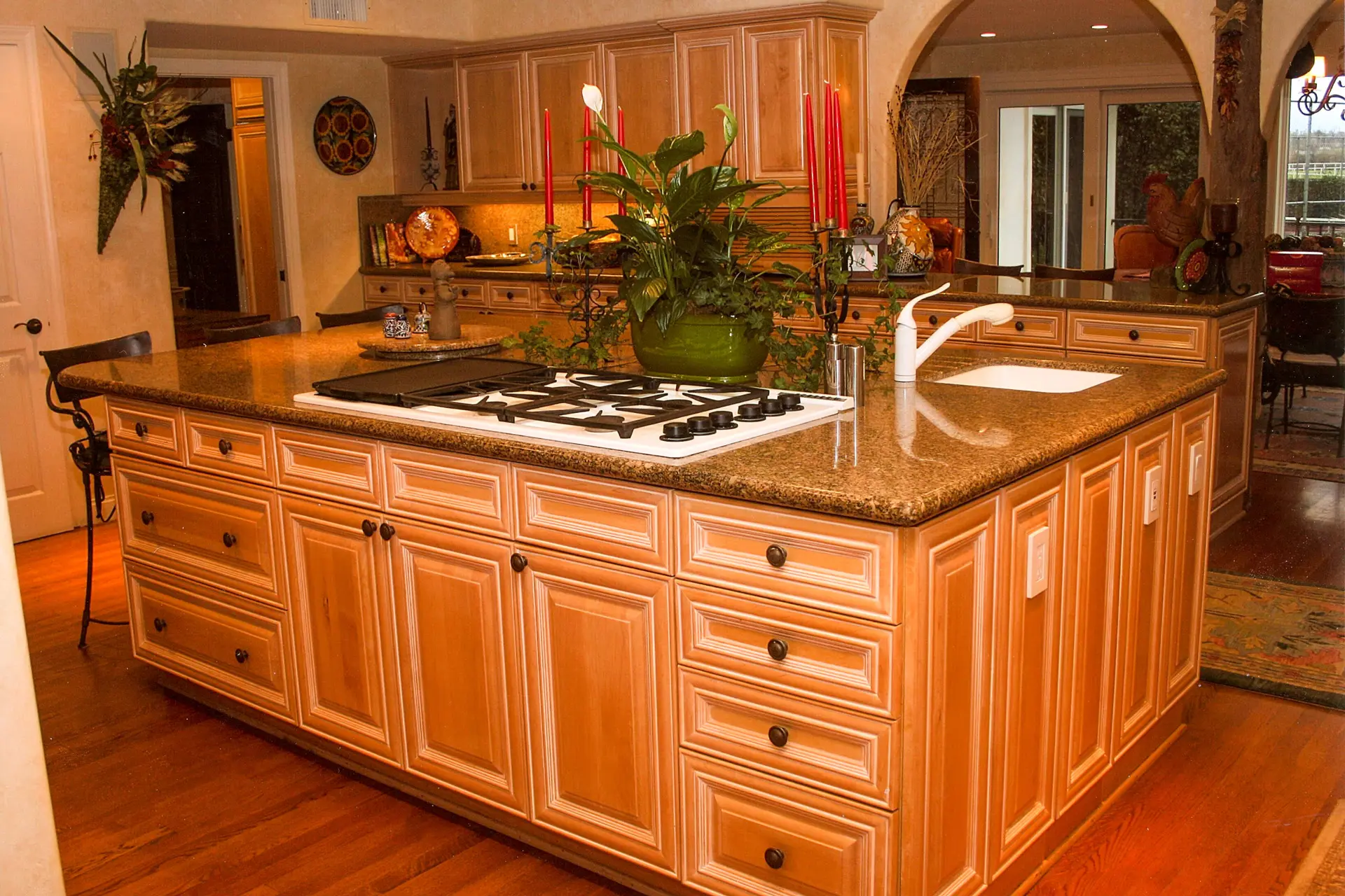 Large kitchen island with granite countertop, gas cooktop, and raised-panel maple cabinetry