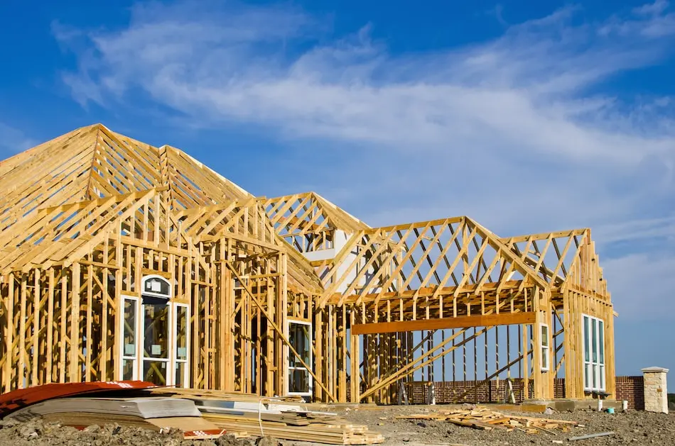 New custom home under construction, framing complete against a blue sky